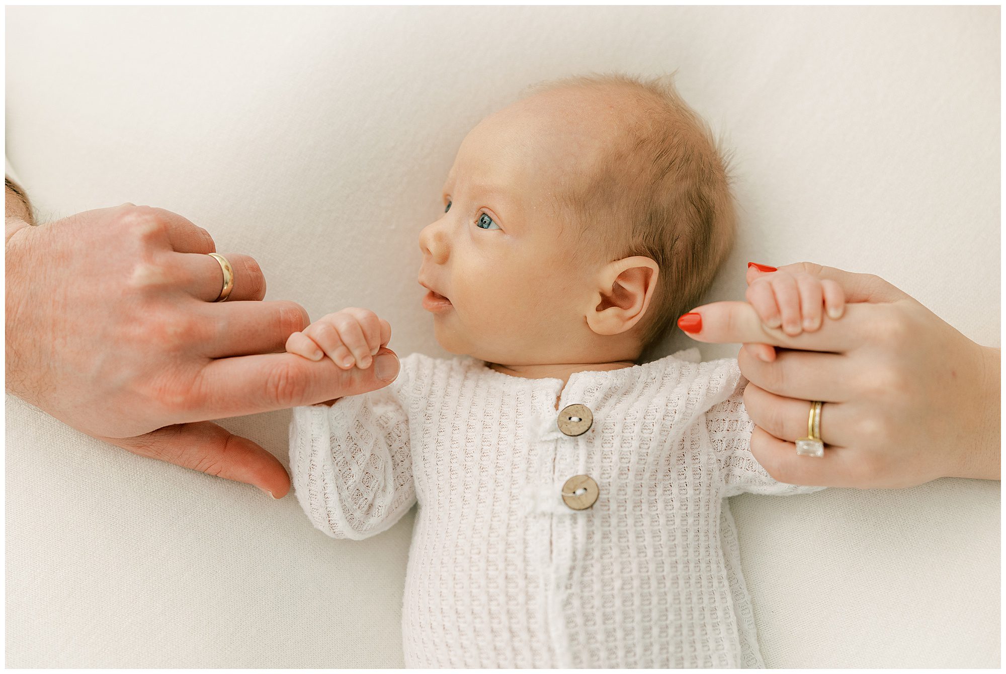 baby holding parents' fingers
