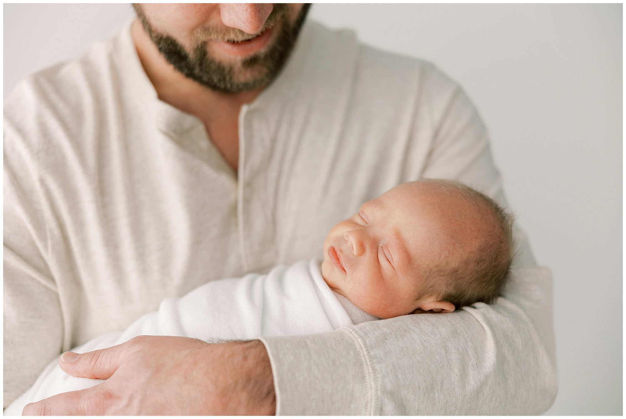 dad holding newborn baby in arms