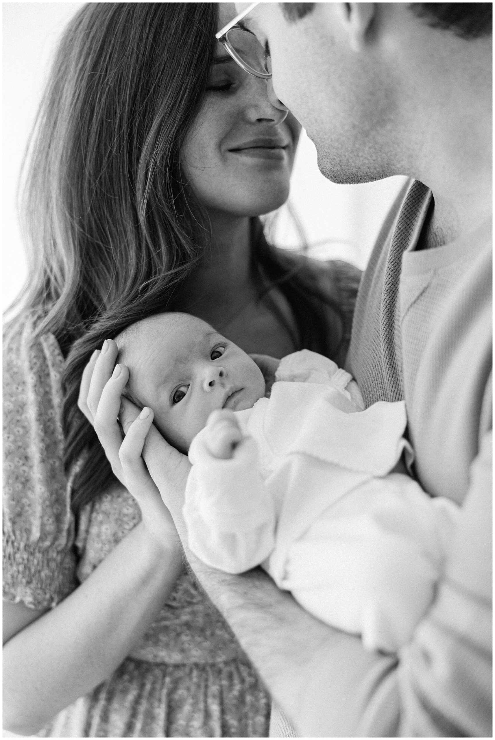 black and white image of mom and dad holding baby