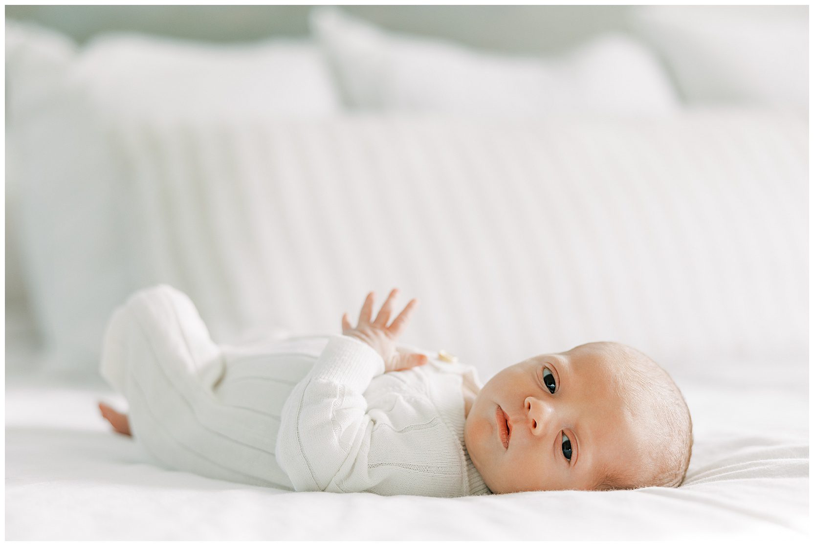 awake baby laying on bed