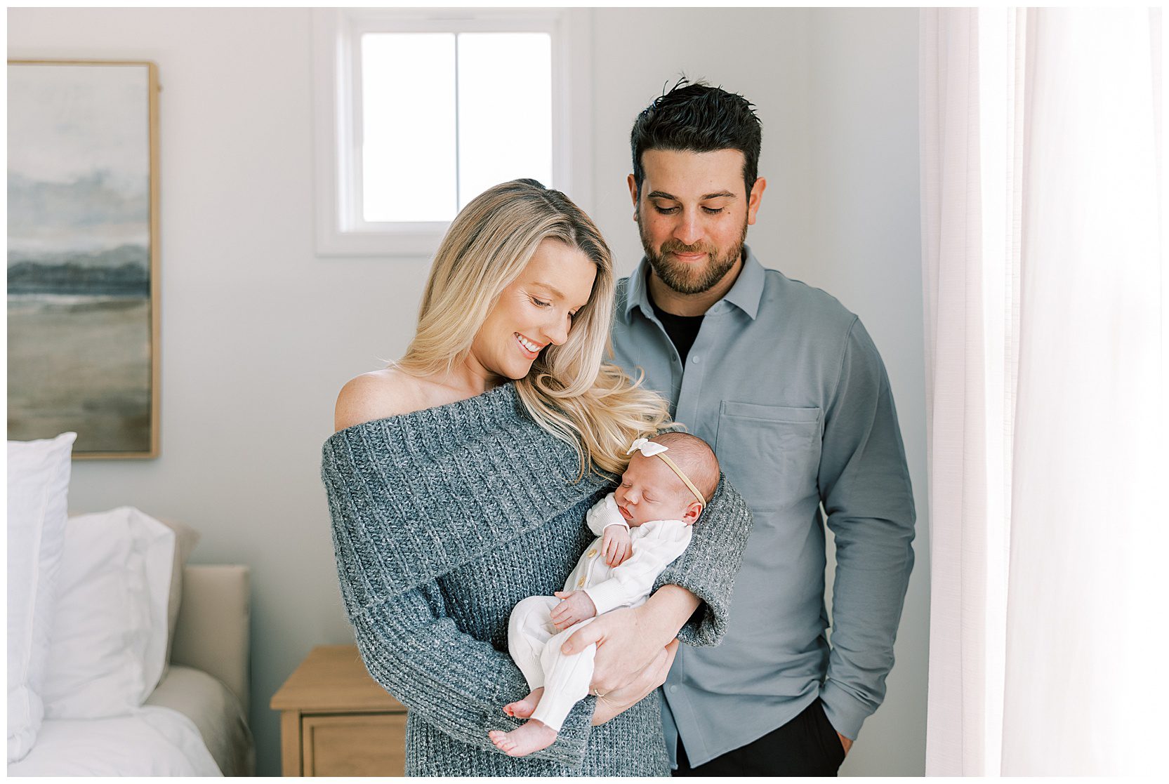 mom and dad smiling down at baby girl