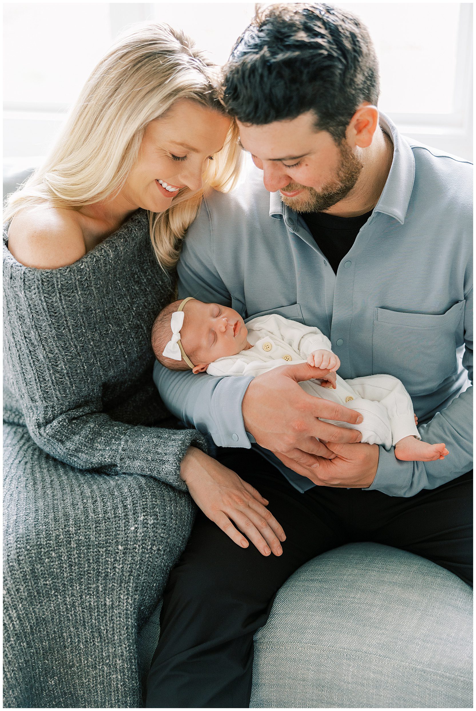 mom and dad with heads touching holding newborn baby