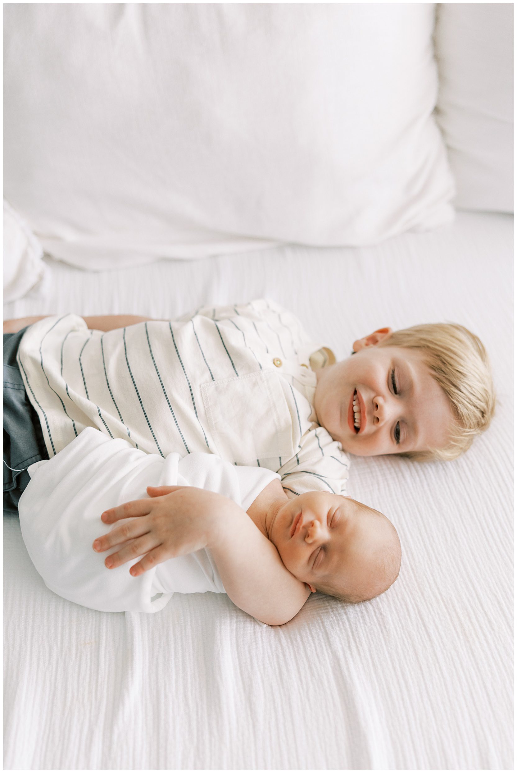 toddler boy holding new baby brother