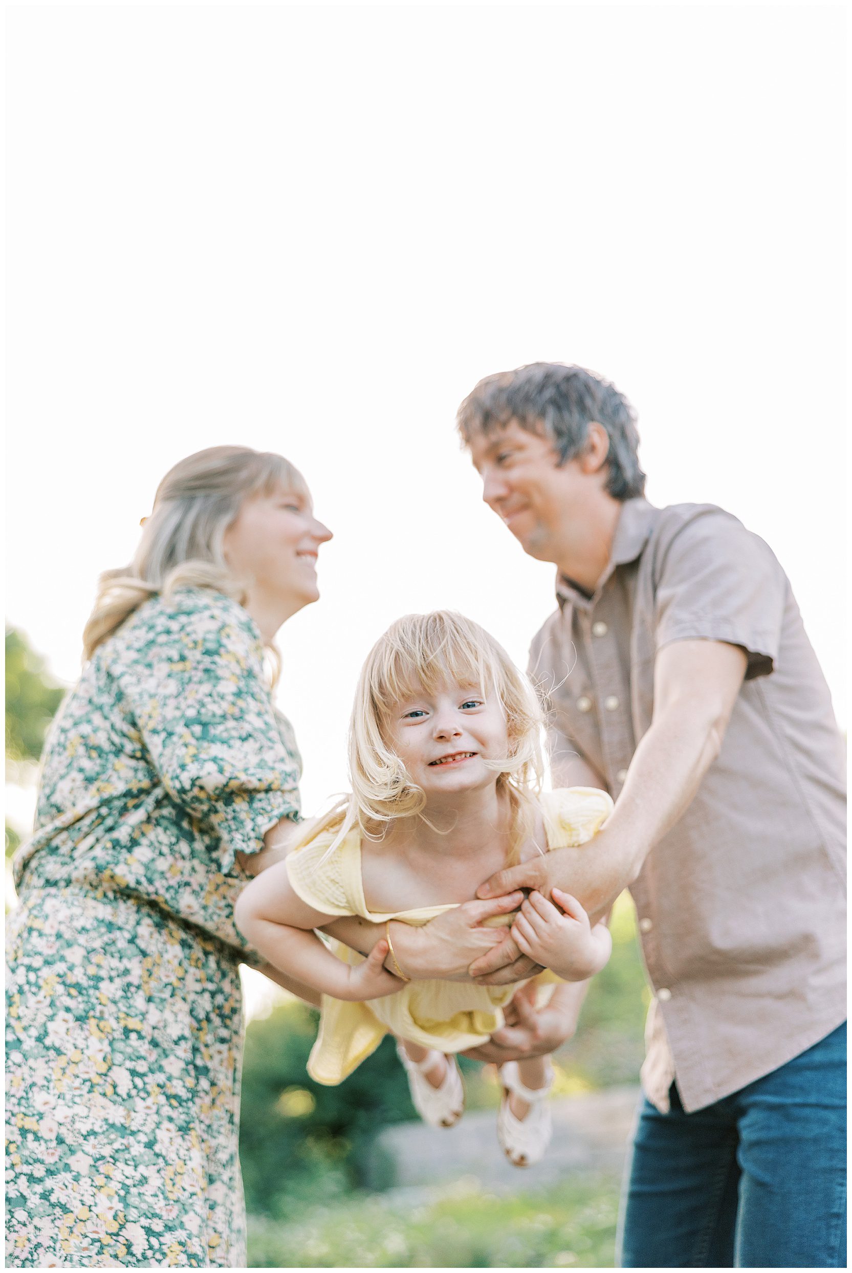mom and dad swinging their daughter, who is laughing