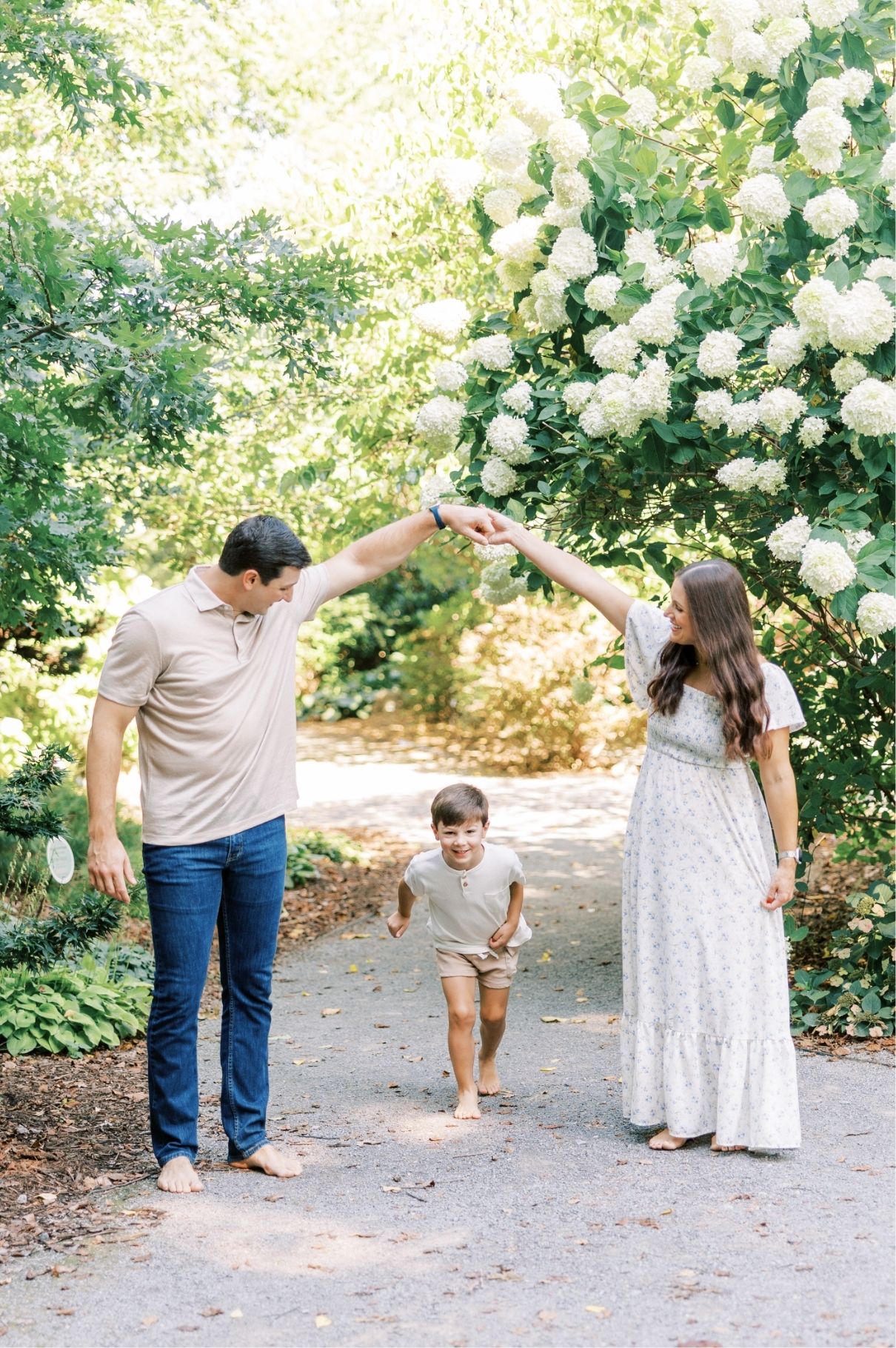 mom and dad holding hands high while son runs underneath