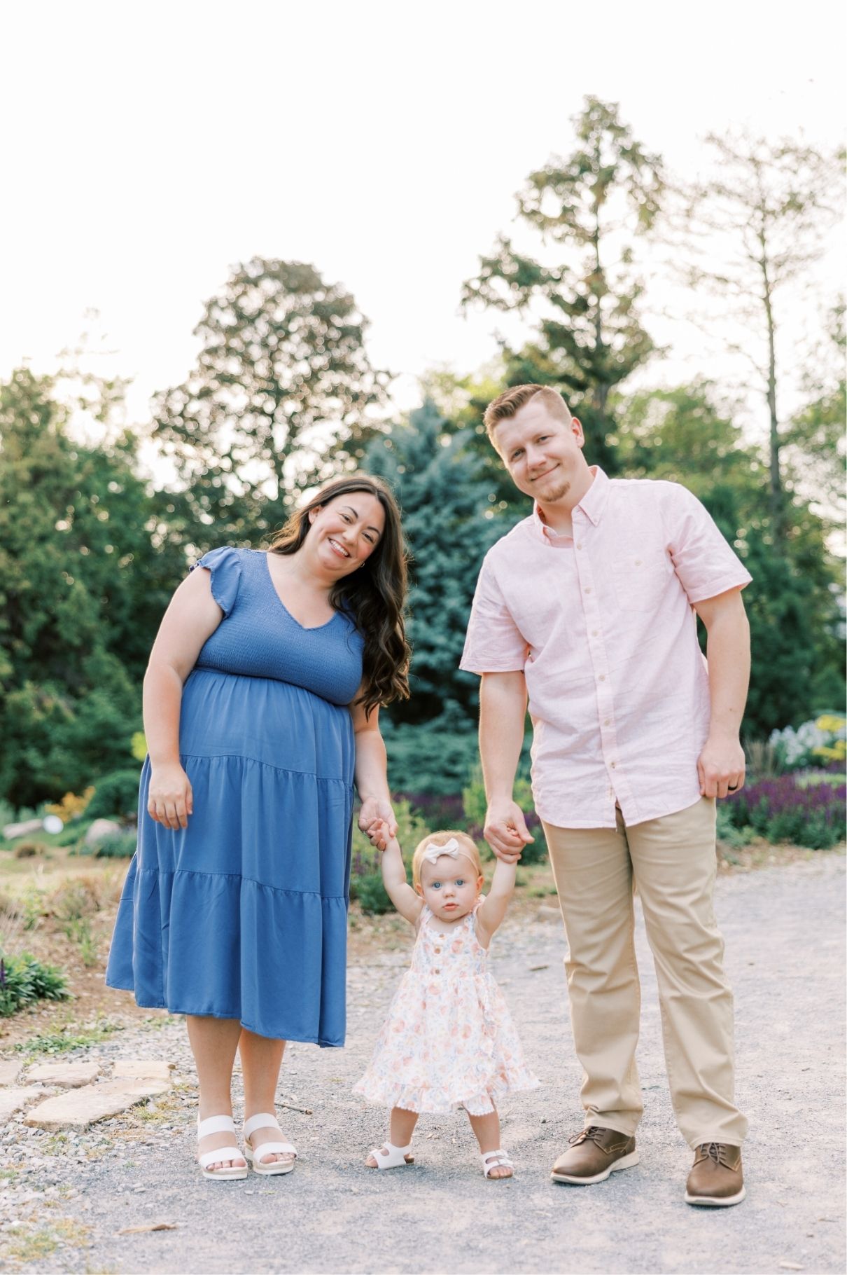 mom and dad holding little girl hands