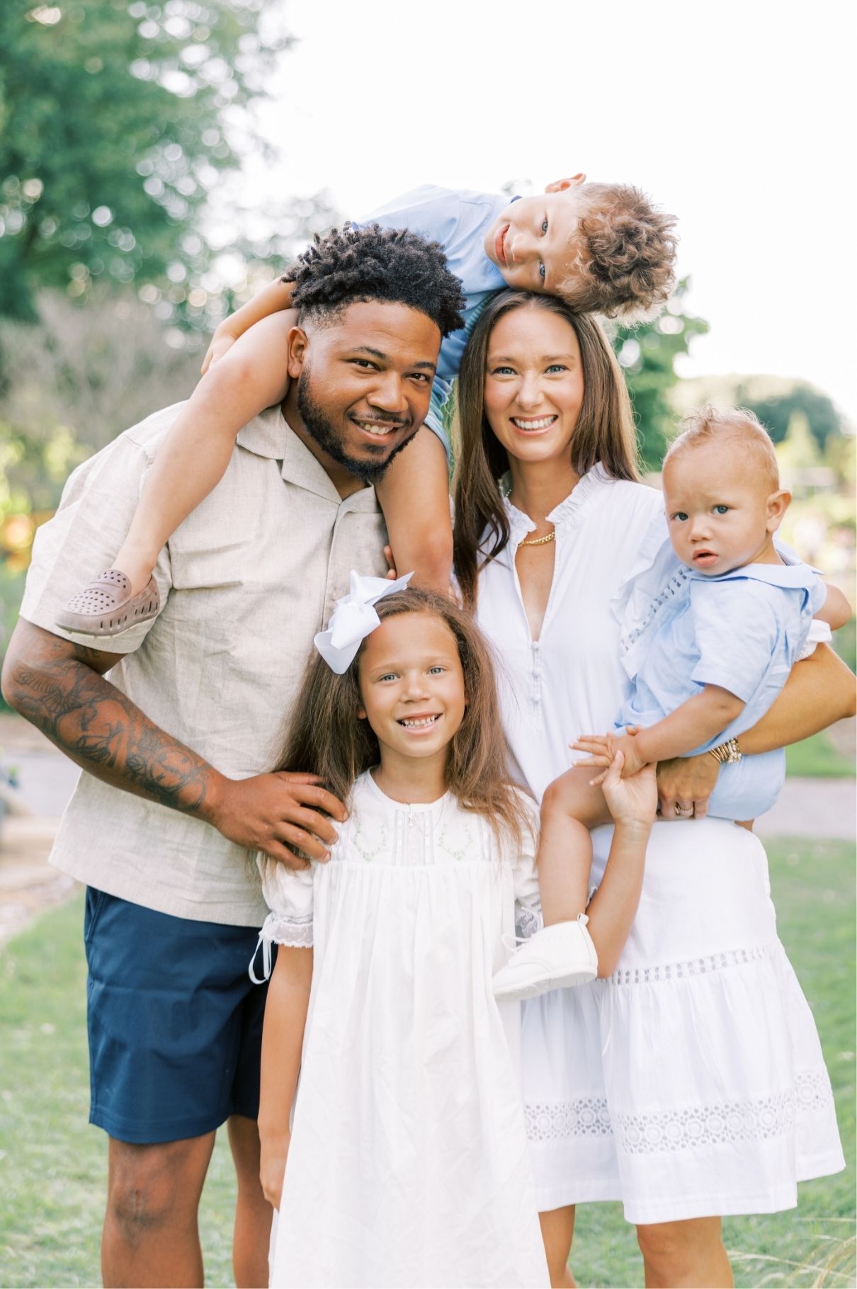 family looking at camera, child on shoulders of dad