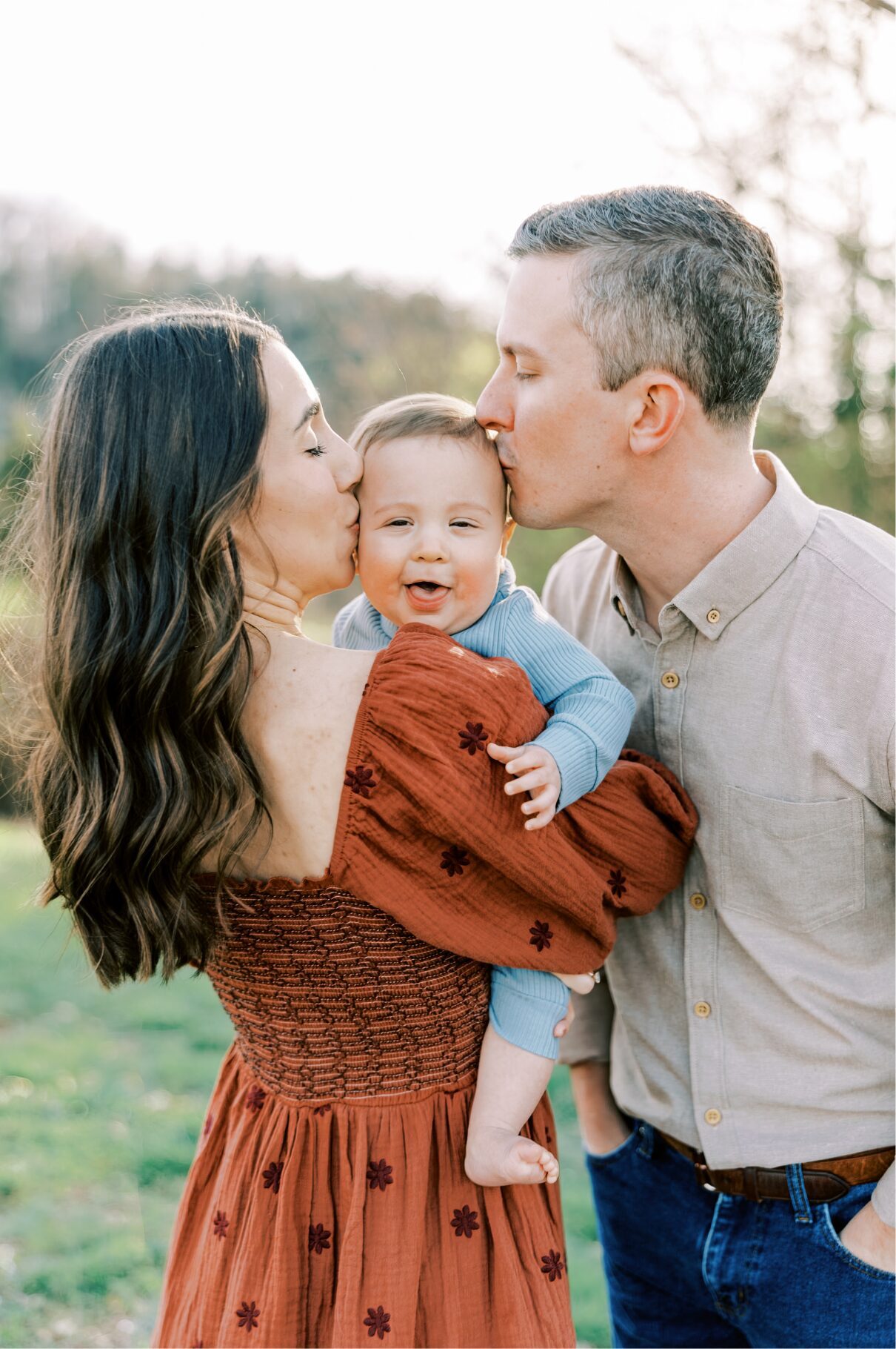 mom and dad kissing boy on head