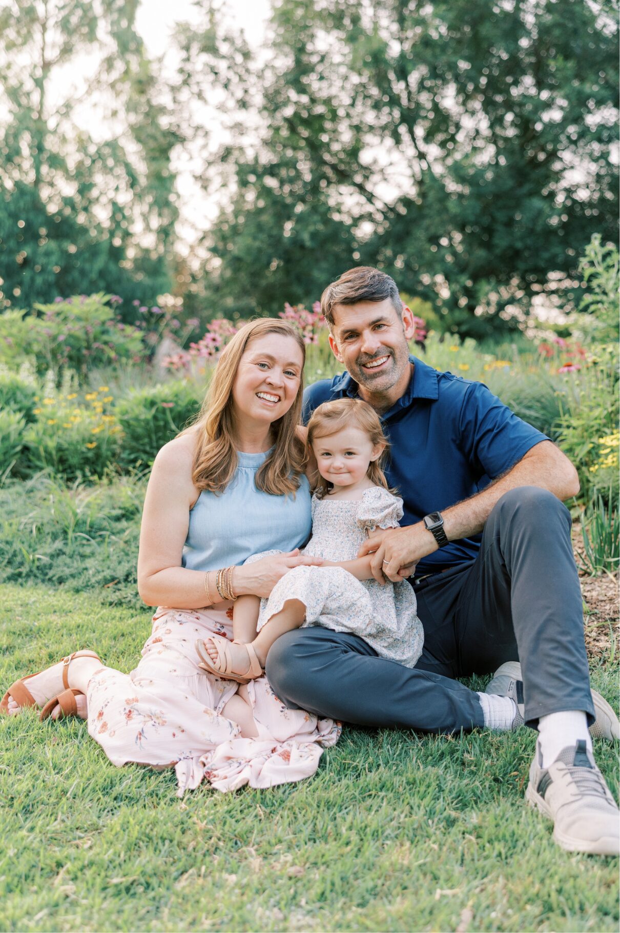family sitting on grass smiling at camera