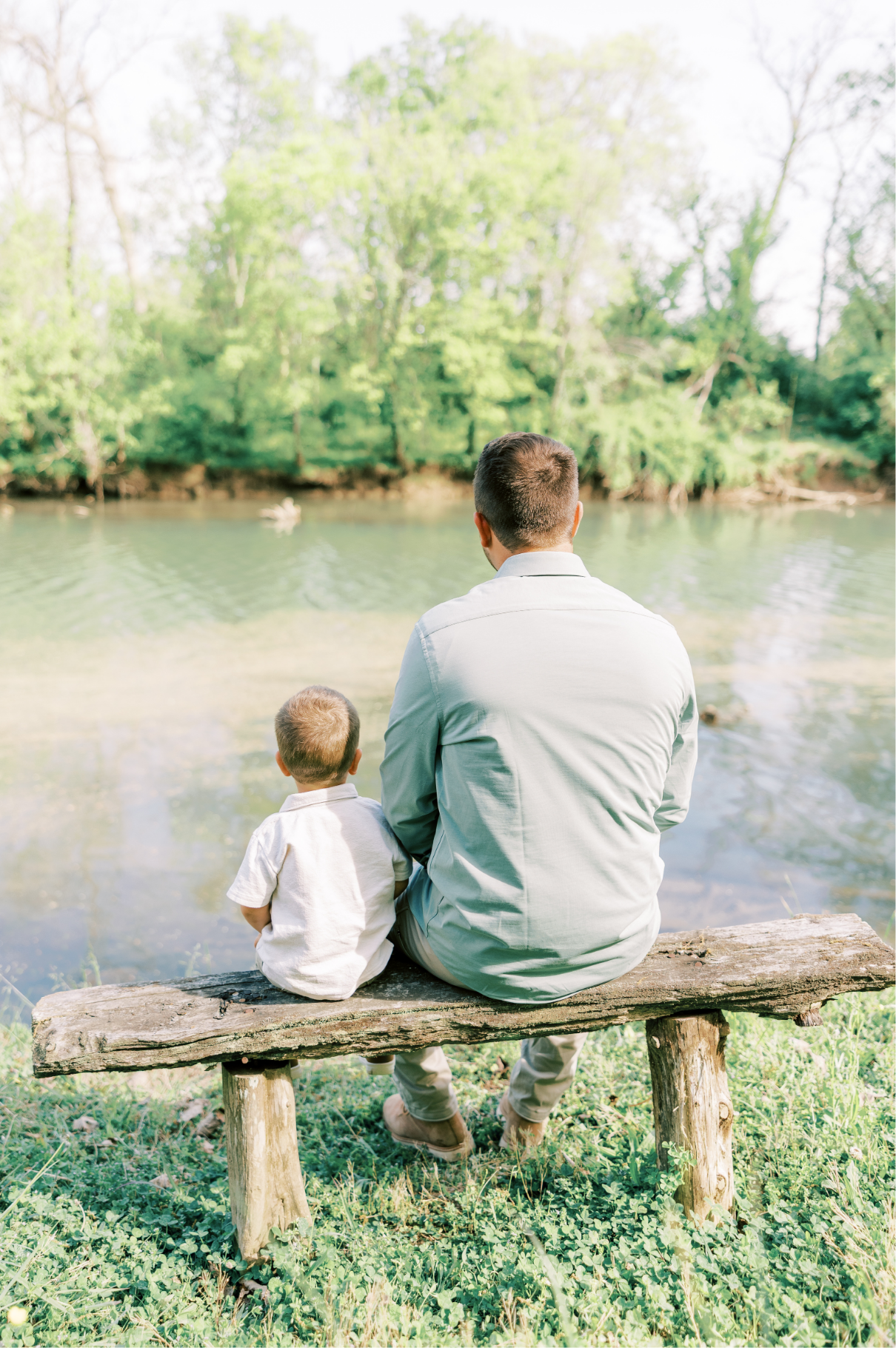 dad and son sitting on bench looking at lake