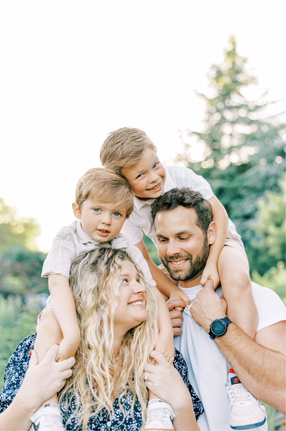boy on mom and dad's shoulders , all smiling at one another